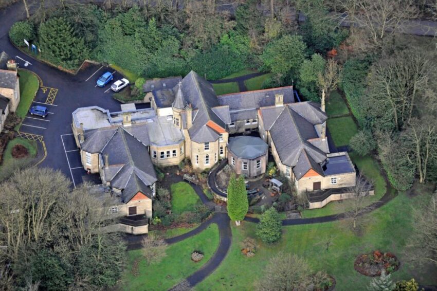 An aerial view of a hospital situated along an encroaching tree-line